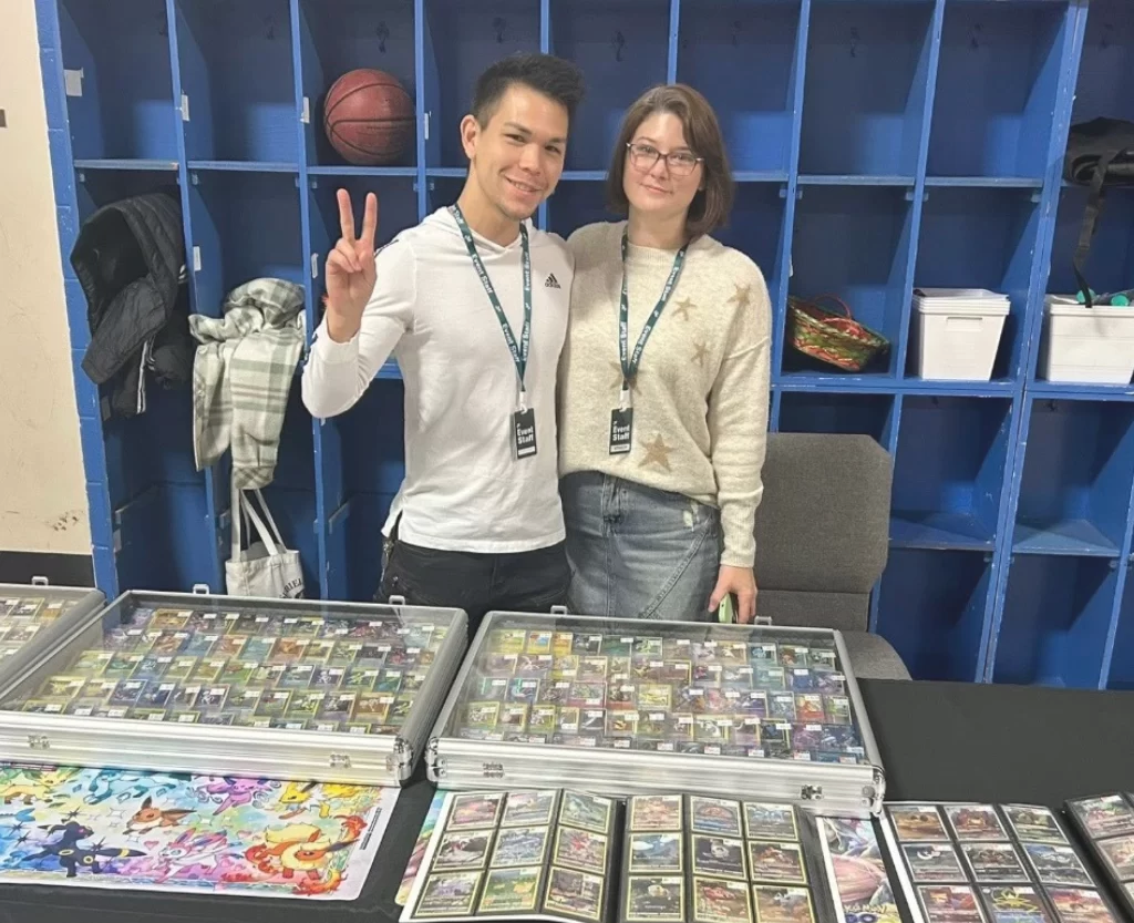 Two people showcasing collectible card binders at a trade show